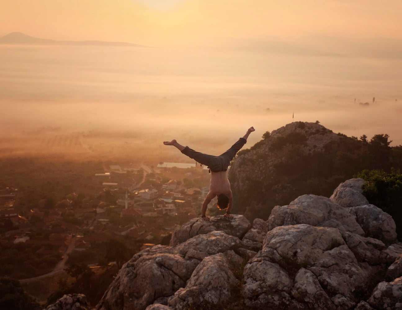 Man handstanding on a rock.